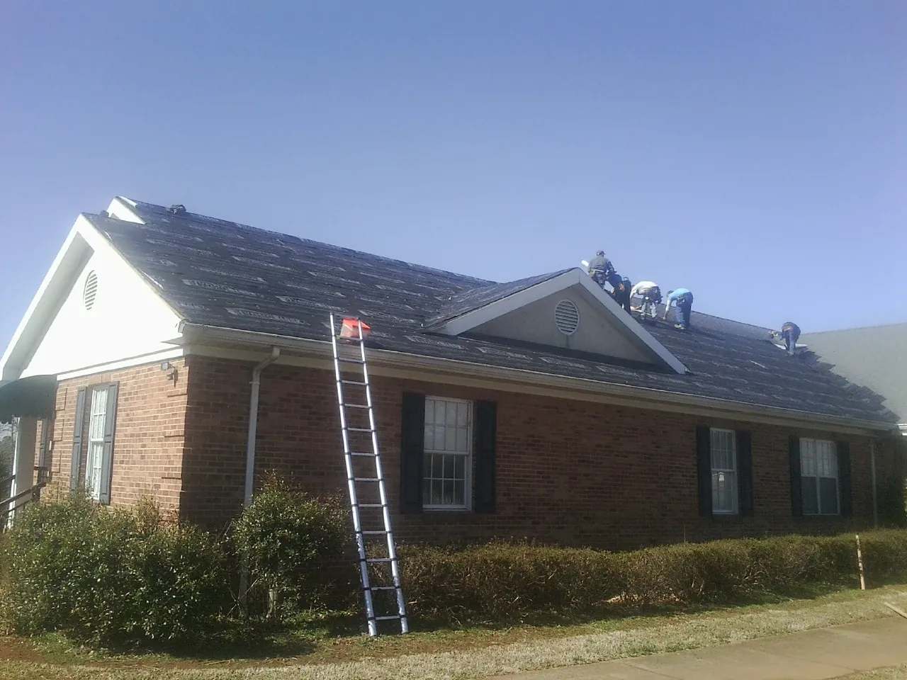 Crew tearing shingles off a brick ranch roof with a ladder set — Metal Roof Repair work by our crew in Sutter Creek