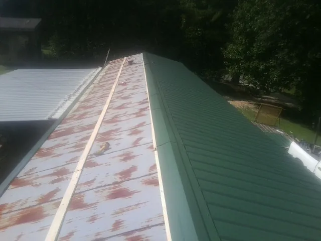 Old rusted panels beside newly installed green metal roofing — Wind Damage Roof Repair by Roofing Brothers in Sutter Creek