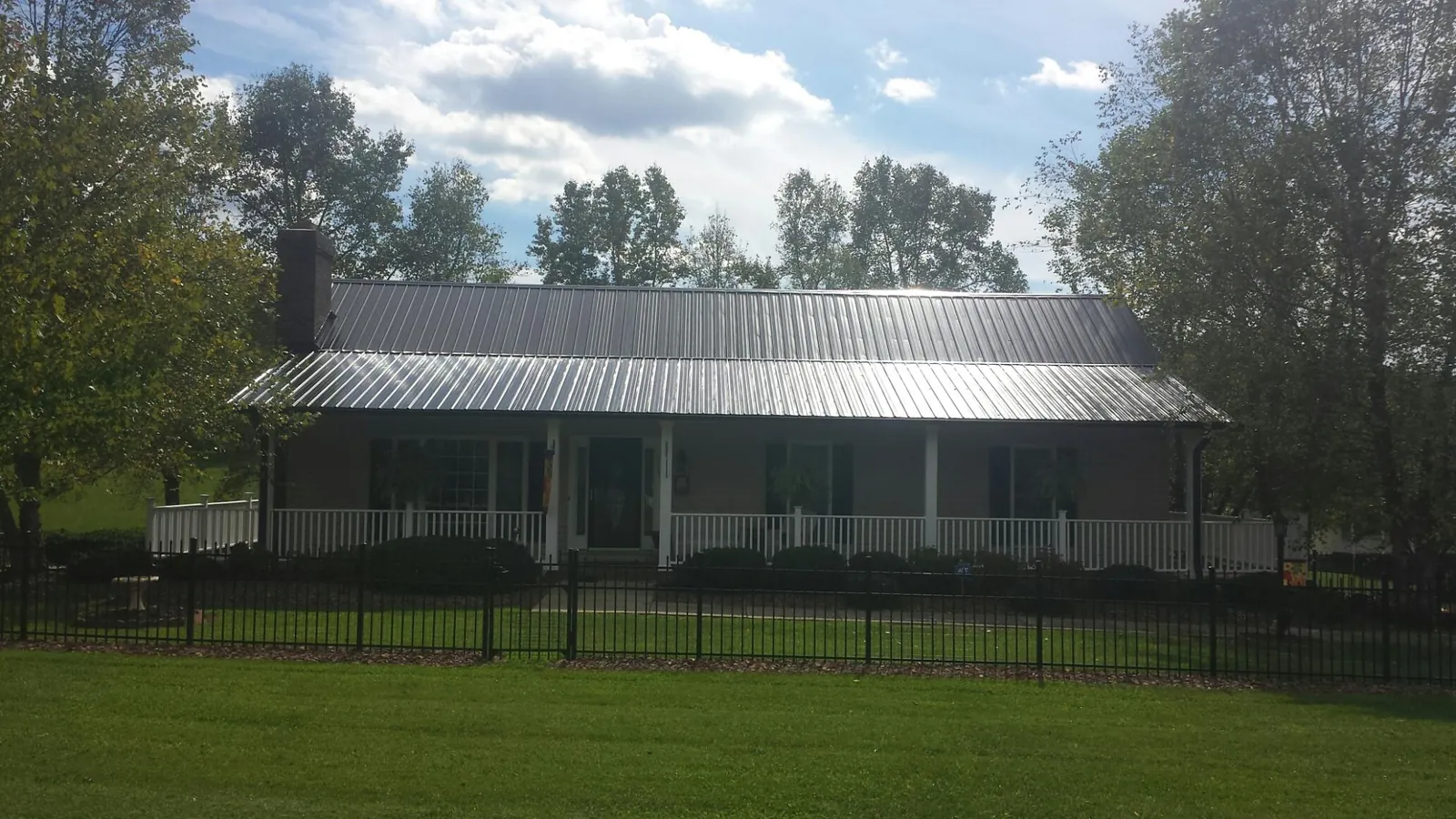 Gray metal roof on a brick ranch with a full width front porch — Gutter Guard Installation work by our crew in Sutter Creek