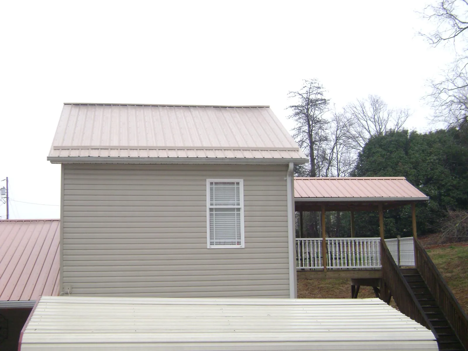 Tan metal roofs on a two story addition and attached porch, from a Roof Replacement job in Sutter Creek